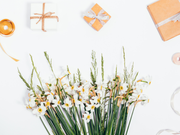 white background with flowers and grass at the bottom and wrapped gifts at the top