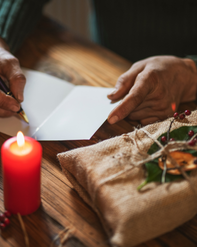 man writing a card with a gift and candle