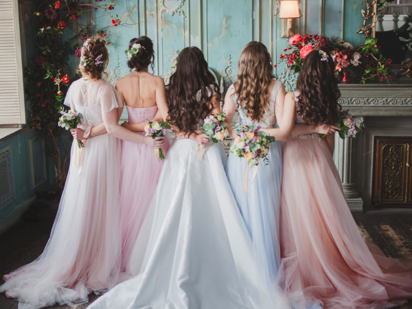 bride and bridesmaids hugging side by side with backs to camera
