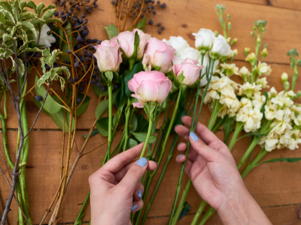 womans hands sorting through different flowers on a table at the florist shop
